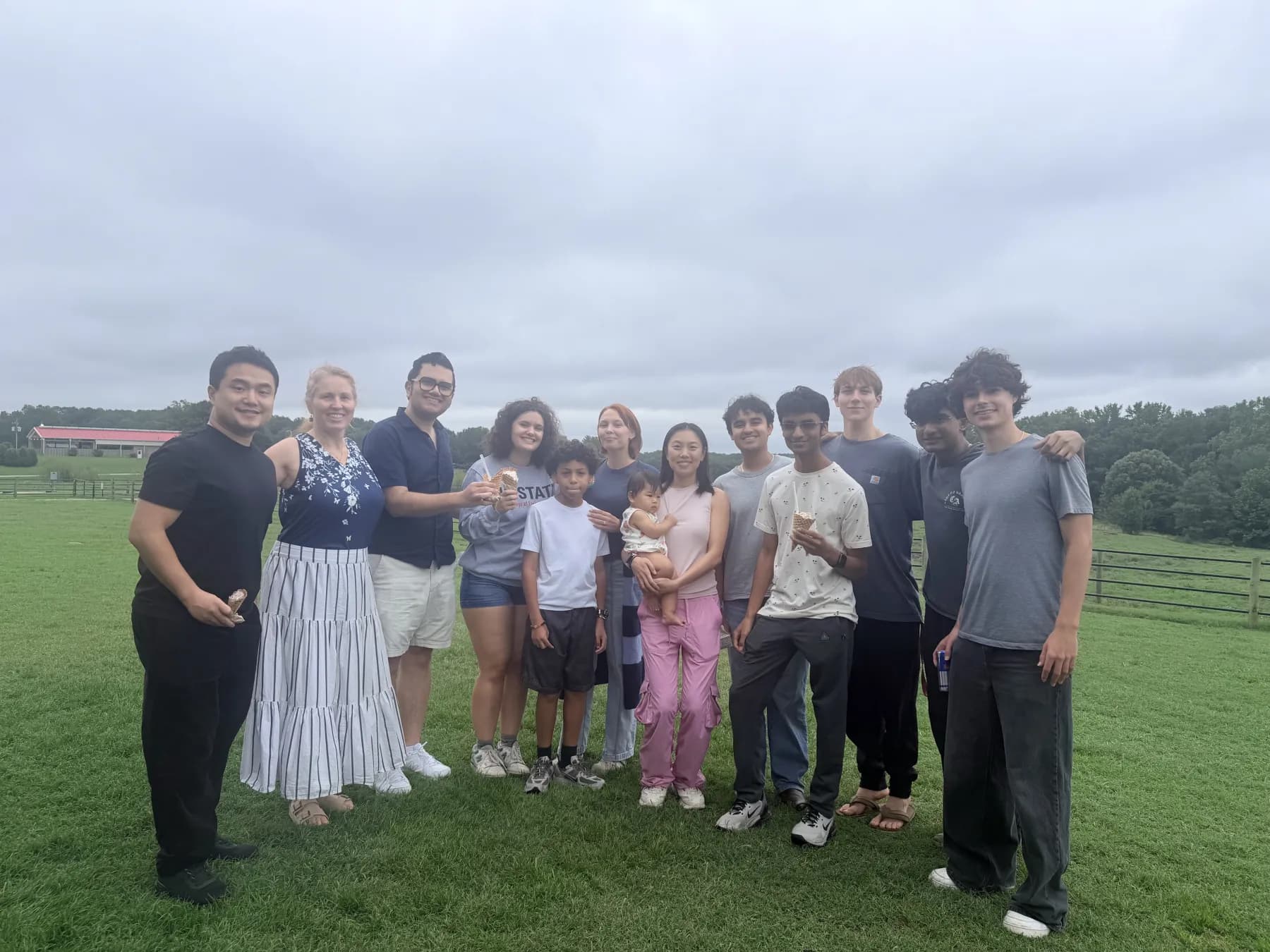 The ExLAIM group standing together on a grassy farm field on a cloudy day.