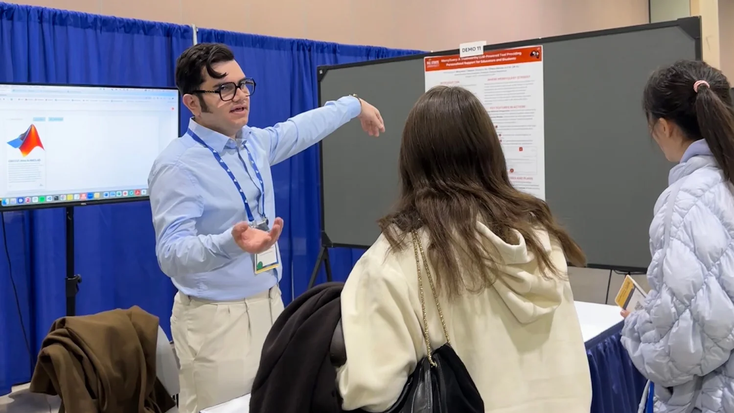 Benyamin Tabarsi explains the MerryQuery poster and live demo to two visitors at AAAI 2025.